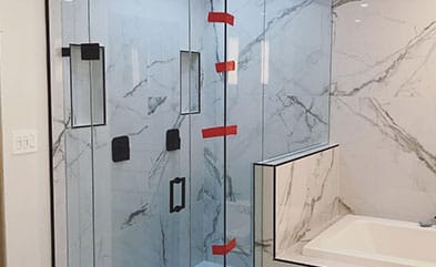 Custom frameless glass shower door installation with matte black hardware in a modern Miami bathroom.