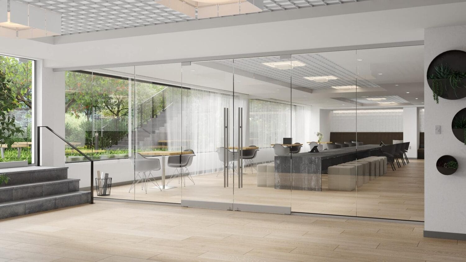 Frameless glass partition system with double glass doors leading into a bright, modern co-working space and open lounge area.