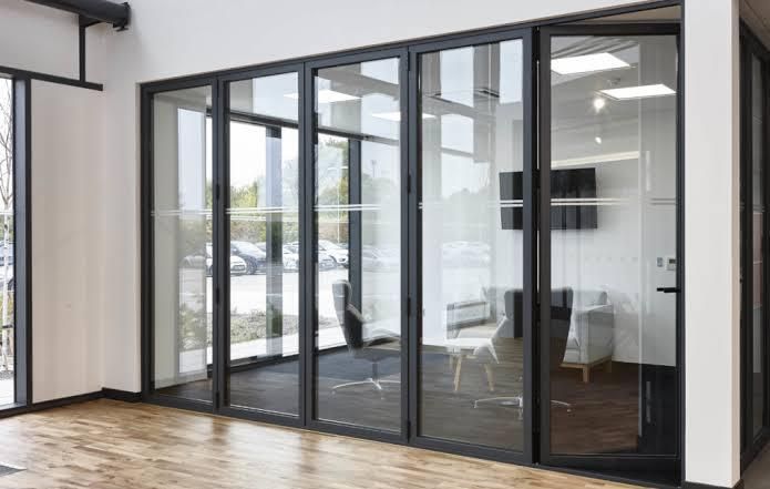 Sliding door Modern glass office partition featuring large floor-to-ceiling glass panels with sleek black aluminum frames and glass doors. The partition creates a bright, open, and professional office environment while providing privacy and a contemporary interior design. The clean glass panels allow natural light to pass through, making the workspace feel spacious and modern.